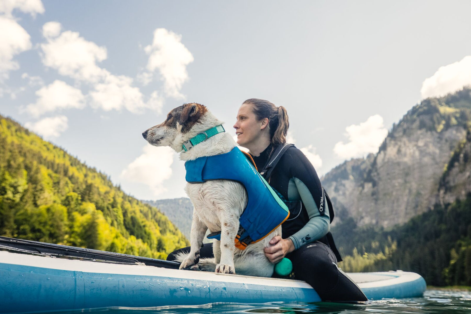 Dog and owner on a paddleboard with mountain backdrop, dog wearing Ruffwear Confluence Collar