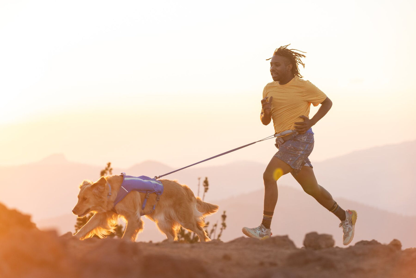 Person and dog running on mountain ridge at dusk using Ruffwear Trail Runner Lead hands-free