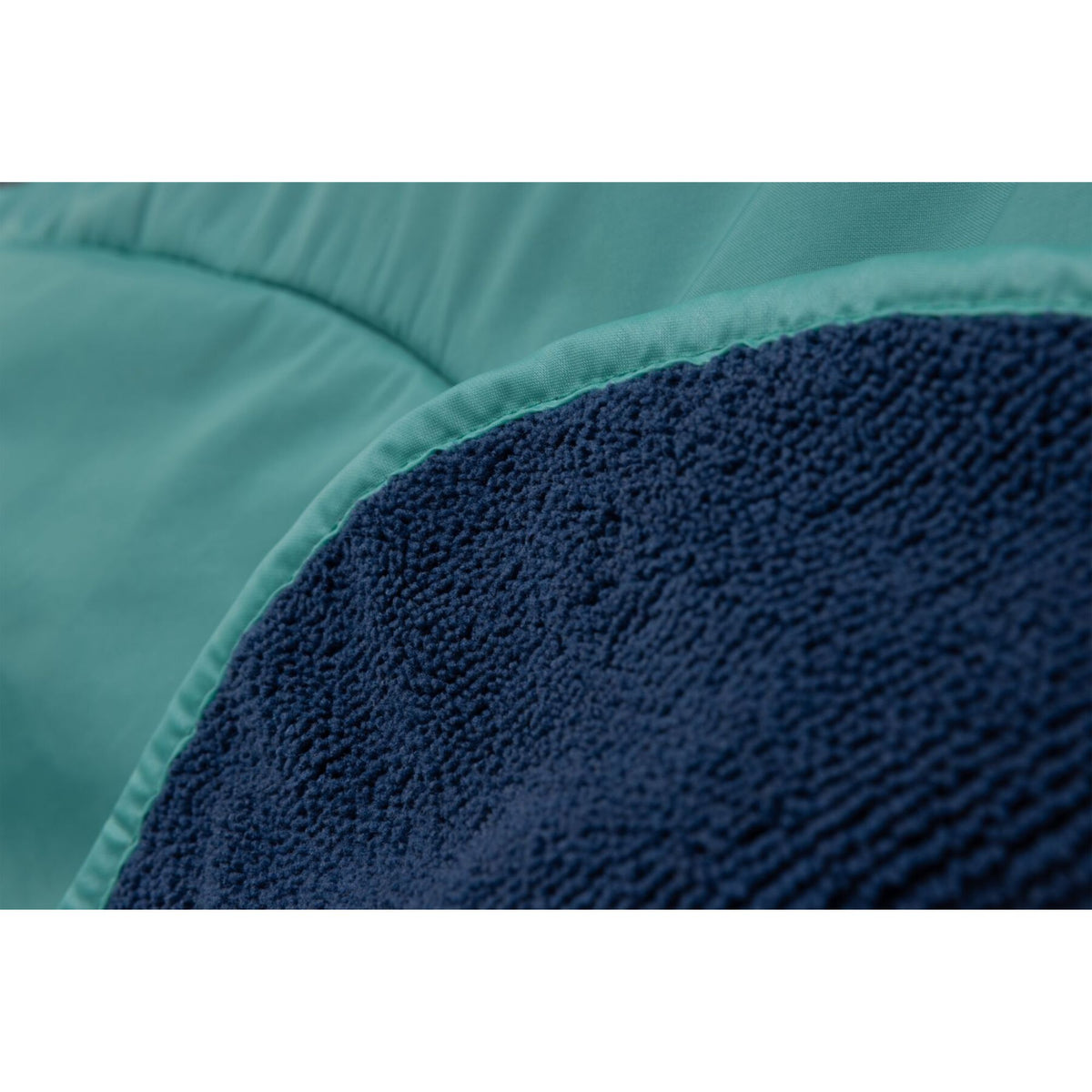 Close-up of the Ruffwear Dirtbag™ Dog Towel showing the contrast between the teal waterproof shell and the textured navy microfiber lining at the edge seam